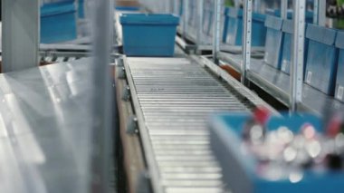 Parcels are seamlessly transported on a conveyor belt system using sturdy blue plastic boxes placed on a roller conveyor. Streamlined Logistics. concept