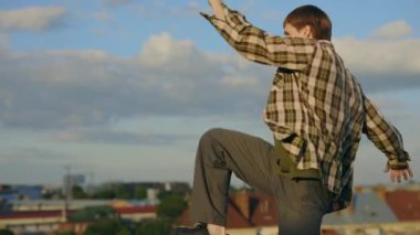 A male Caucasian hip-hop dancer performing impressive movements and gestures, showcasing his skills on a rooftop