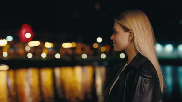深夜站在湖畔的金发美女 的侧视图 观看城市之光 感受自由 人的概念 — 图库视频影像