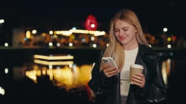 Gece Şehri 'nde dikilirken Modern Akıllı Telefonu kullanan Çekici Genç Bayan, İnternet Tutma Kahvesi' ni arıyor. Profesyonel Kadın İşveren Cep Telefonu Dışarısında Metin Yazıyor