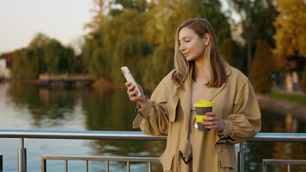 Χαριτωμένη Νεαρή Γυναίκα Στέκεται Έξω Χρησιμοποιώντας Smartphone Γραπτών Μηνυμάτων Τους — Αρχείο Βίντεο