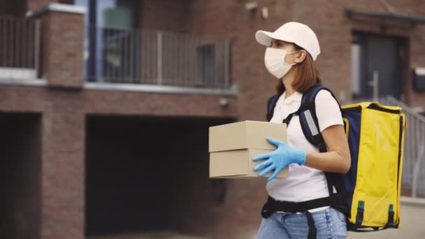 여자의 상자를 마스크와 장갑을 노란색 배낭을 전염병 코비드 노동자 포스트 — 비디오
