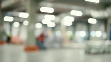 Muazzam Perakende Deposu 'nun bulanık görüntüsü, karton kutulara konmuş raflarla dolu. İşçiler tarama yapıyor, paketleri sıralıyor. Dağıtım ve Teslimat Merkezi