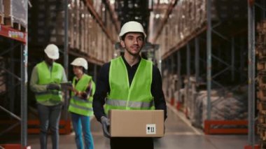 Hard Hat 'teki yakışıklı işçi eşyalarla dolu perakende deposunda karton kutu taşıyor. Yoğun Lojistik ve Dağıtım Merkezi 'nde çalışıyorum. Nakliye ve Teslimat Servisi Konsepti
