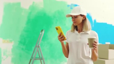 Kadın işçi ayakta duruyor, duvarları boyayıp kahve içerken müşterilerle mesajlaşıyor. Özel üniformalı bir kadın molada telefonunda uygulama kaydırıyor. İnsanlar ve teknoloji kavramı