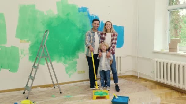 粉刷完墙壁后 一家人站在新公寓里的画像 妻子和儿子躺在绿蓝的墙背景上 室内设计 新公寓 — 图库视频影像