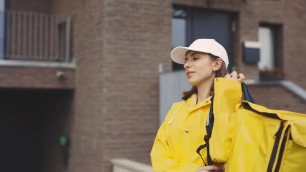 Happy Cute Caucasian Woman Courier Raincoat Walking Building Snelle Levering — Stockvideo
