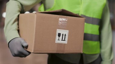Erkek işçi perakende deposunda duruyor, elinde karton kutu var. Lojistik ve Dağıtım Merkezi 'nde çalışıyorum. Ön Ağır Çekim Çekimi. Kapat.