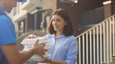 Beyaz Adam Özel Üniformalı Kurye Pozitif Güzel Bir Kadın 'a yiyecek paketi teslim ediyor. Kadın tarikatı alır. Yemek teslimatı. Erkek İşçi Ev Teslimatı. Man Teslimat Ürünleri