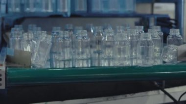 Plastik şişeler konveyörde hareket ediyor. Plastik Boşluklar Doğrusal Taşıyıcı boyunca ilerler. Plastik şişelerin toplanması Geri Dönüşüm Konseptini temsil eder