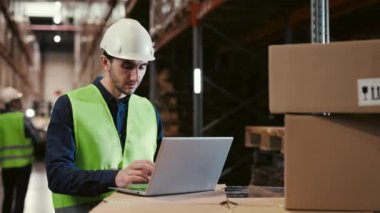 Uluslararası Çevrimiçi Alışveriş Şirketi için Modern Lojistik Merkezi 'nde çalışan erkek çalışan. Siparişleri ve Dağıtım Hattı Teslimatlarını İyileştirmek İçin Bilgisayarı Kullanan Adam