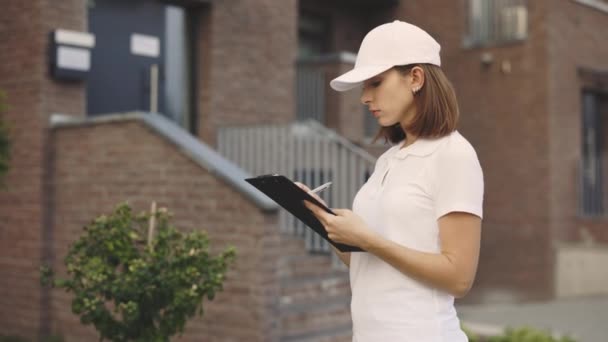 Portrait Young Caucasian Mailwoman Looking Writting Documents Tablet Finding Clients — Video