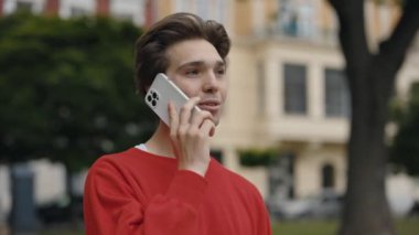Adam yürüyor, sokakta arkadaşlarıyla cep telefonuyla konuşuyor. Gülümseyen Adam dışarıda bir telefon görüşmesi yapıyor. Dışarıda telefonlu neşeli bir erkek. Smartphone Kullanan Öğrenci Dışarıda