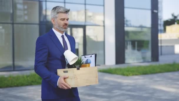 Przygnębiony Biały Pracownik Biurowy Wychodzi Budynku Centrum Biznesowego Niosąc Pudełko — Wideo stockowe