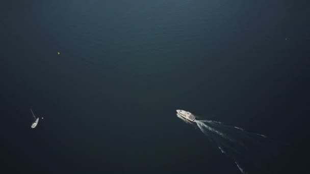 在深蓝色的海面上 航拍到一艘令人惊奇的游艇的景象 创造了白蛇 摄象机跟随船在科莫湖蓝色水域 海洋旅游及旅游概念 — 图库视频影像