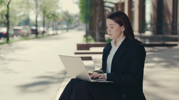 働く目的のためにラップトップを使用して階段に座っている慎重なビジネス女性の側面のビュー ラップトップを使用して正式なスーツの女性 オフィスの背景にクライアントとテキスト — ストック動画