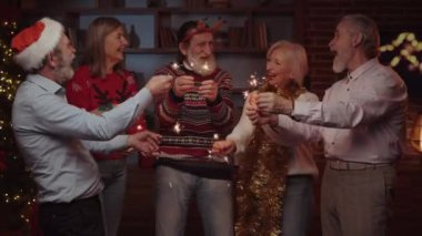 Yaşlılar birlikte eğleniyor, Sparkles 'ı tutuyor ve oturma odasında dans ediyor. Yeni yıl partisinin kutlaması. Olgun insanlar şarkı söylüyor, gülüyor ve eğleniyor.