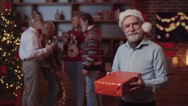 Dojrzały Mężczyzna Stojący Noszący Kapelusz Mikołaja Trzymający Pudełko Prezentów Świątecznych — Wideo stockowe