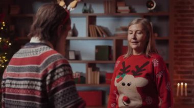 Son sınıf öğrencisi, dekoratif şenlik arka planında birlikte duran karısına hediyesini sunar. Kış tatilini kutlayan yaşlı bir çift. Noel Neşe ve Hediye Veren Ruh