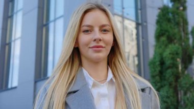 Kendine güvenen ve başarılı genç, beyaz saçlı, takım elbiseli bir iş kadını ofis binasının dışında kameraya bakıyor. İnsan portresi. İş Kadını Kişisi