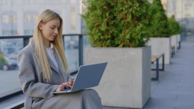 Genç Sarışın Çekici İş Kadını Portatif Bilgisayar ile bir bankta çalışıyor. Bayan Daktilo dışarıda dizüstü bilgisayarda. Öğrenci Mesafesi Çalışması. Teknoloji ve İnsanlar Konsepti