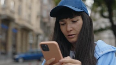 Sıradan kıyafetli genç bayan Smartphone 'a bakıyor ve alışveriş merkezinin yakınında dururken iyi haberler okuyor. Şaşkın Kadın Telefonla Zaferi Kutluyor. Kazan.