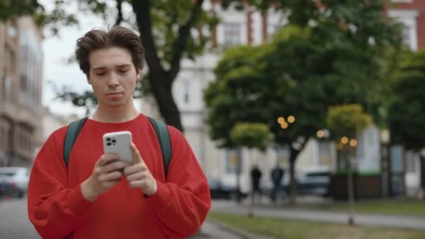 Jovem Caucasiano Bonito Roupas Casuais Usando Smartphone Enquanto Caminhando City — Vídeo de Stock