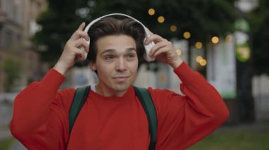 Dijital Kulaklık Giyen Modern Kafkas Adam, Sokakta Yürürken Akıllı Telefonundan Müziğin Zevkini Çıkartıyor. Gündelik giysiler içindeki yakışıklı erkek gülümsüyor ve keyifli.