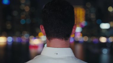 Resmî tişörtlü genç bir iş adamının geçmişe bakışı. Gece Şehrin Dışında Duran Turist, Şehir Binalarına Bakıyor ve Embankment 'ta Gecenin Sonlarına Kadar Eğleniyor