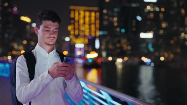 Joven Serio Usando Smartphone Mientras Está Parado Calle Night City — Vídeo de stock