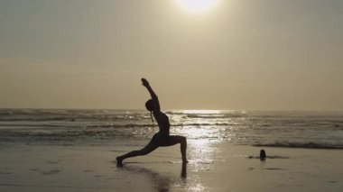 Kafkas Koçu, Virabhadrasana 'yı Sahilde Savaşçı Pozu Veriyor. Sahilde Spor Kız Eğitimi. Slim Lady Esneme. Yoga ve Spor Konsepti
