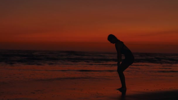 女子训练员在新鲜空气中训练 瘦弱的女人在日落的海滨伸展着她的背脊 体能训练体育与人的概念 — 图库视频影像