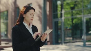 Resmi takım elbiseli iş kadını iş için dışarıda tablet kullanıyor, mesaj ve uygulama çalıyor. Ofis çalışanı dışarıda. İş ve İletişim