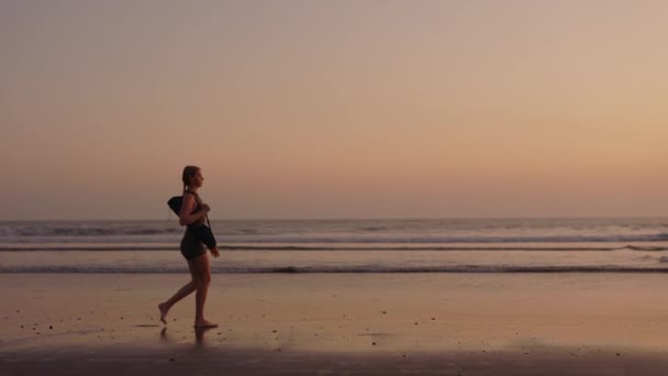 苗条的女运动员在训练后沿着海滩散步 教练心平气和地沿着海滨散步 体育与人的概念 — 图库视频影像