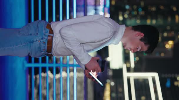 Vertical Video Guy Walking Night City Using His Phone Browsing — Stock Video