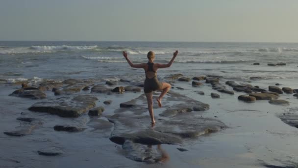 在阳光日户外海滩上做瑜伽的瘦小金发女孩的背景图 外面的年轻女子训练 教练伸展户外 瑜伽和体育概念 — 图库视频影像