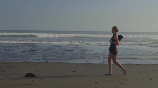 在瑜伽运动服海滩赤脚散步的迷人的女运动员 白种人女教练下课后沿着海滨散步 美丽活泼的女士在散步 体育与人的概念 — 图库视频影像