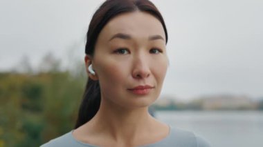 Sakin bir yaz sabahı kameraya bakan güzel, sağlıklı Asyalı kadının portresi. Gülümseyen, tatlı kız dışarıda dinleniyor. Güç egzersizinden ve fiziksel aktiviteden sonra. Kapat.