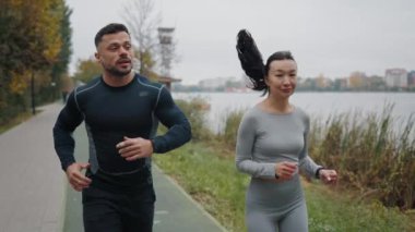Erkek ve kadın parkta birlikte koşuyorlar, spor kıyafetlerini giyip yaz sporu antrenmanına gidiyorlar, yavaş çekimde çekiyorlar. Spor çifti