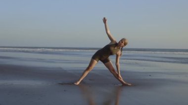Spor Giyim 'de Güzel Sarışın Kadın Sahilde Egzersiz Yapıyor. Sahilde Kadın Eğitimi. Yoga yapan koç. Yoga ve Spor Konsepti