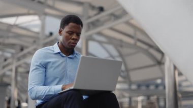 Yakışıklı Afrikalı Amerikalı Öğrenci, dışarıda, kampüs merdiveninde oturan bir bilgisayarın üzerinde ders çalışıyor. Girişimci Mesafe bir dizüstü bilgisayar üzerinde çalışıyor. Halk ve Teknoloji