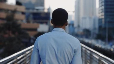 İş Bölgesi 'ndeki Gömlekli Yürüyen Köprü' deki Başarılı Genç Afro-Amerikan Adam 'a geri dönüş. İş Adamı İşe Giderken Şehrin Arkasından Yürüyor. İnsanlar Konsepti