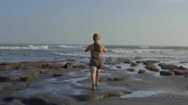 Gri Spor Giyim Giyimli Kafkas Sarışın Kız Sahil kenarında Yoga Egzersizleri Yapıyor. Beden eğitimi. Esniyorum. Yoga ve Spor Konsepti