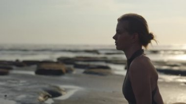 Deniz kıyısında oturan dalgın ve çekici kız uzaklığa doğru bakıyor. Dışarıda Rüya Gören ve Geleceğe Bakan Büyüleyici Kadın. İnsanlar Konsepti