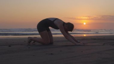 Sporty Girl, Sahil kenarındaki Mat 'te çalışıyor, Sırt ve Omurga için Çeşitli Egzersizler yapıyor. Çekici, iyi giyimli ince kız esnemeleri. Açık havada Atletik Kadın. Yoga ve İnsanlar Konsepti