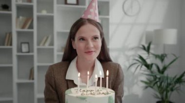 Ofisteki Doğum günü Kızı Pastadaki Mumları Üflüyor. Tatil havası. Beyaz tenli, gülümseyen kız doğum gününü pastayla kutluyor. Doğum Günü Konsepti