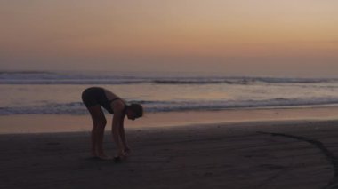 Slim Kafkasyalı Kız, Deniz kıyısında Yoga yaptıktan sonra egzersiz minderini sarıyor. Sporcu kadın antrenmandan sonra. Halk ve Spor Konsepti