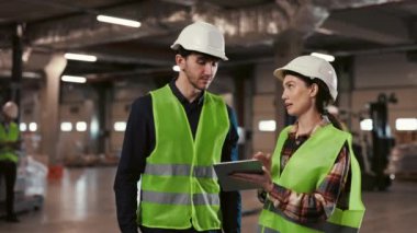 Güvenlik teçhizatındaki iki endüstri mühendisi, bir depo ortamında dijital tablet üzerine profesyonel bir tartışmaya giriştiler.