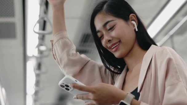Lady Gripping Handrail Subway 浏览社交网络 欣赏手机音乐 迷人的女孩在乘坐公交时使用智能手机 车上还带着耳机里的音乐 旅行和技术概念 — 图库视频影像