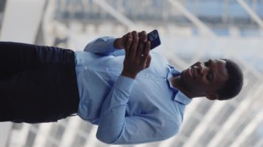 Dikey video. Heyecanlı Afro-Amerikan Adam ve Smartphone zaferi kutluyor. Mutlu Çoklu Etnik Adam Telefonundan İyi Haberler Aldı. İnsanlar ve Duygular Konsepti